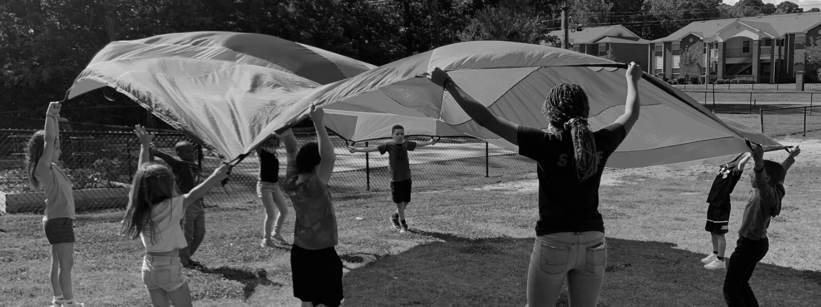 Volunteer plays parachute with a group of children.